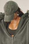 Close up side view of model wearing the six-panel washed green Official Cap with a curved brim and an embroidered upside down Joah Brown logo on the front