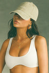 Side view of model wearing the six-panel desert Official Cap with a curved brim and an embroidered upside down Joah Brown logo on the front