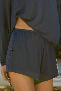 Close up side view of model from the waist down posing in the relaxed-fit navy modal Easy Short with an elastic waistband, side pockets and subtle pleating for added shape and dimension