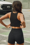 Back view of model posing in the street wearing the fitted, full length vintage black flexrib Henley Tank with a notched henley neckline