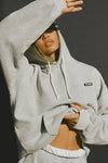 Front view of model posing in the oversized comfortable classic grey french terry Oversized Pullover Hoodie sweatshirt with a Joah Brown logo patch at the front left chest, kangaroo pocket, drawstrings and thumbholes