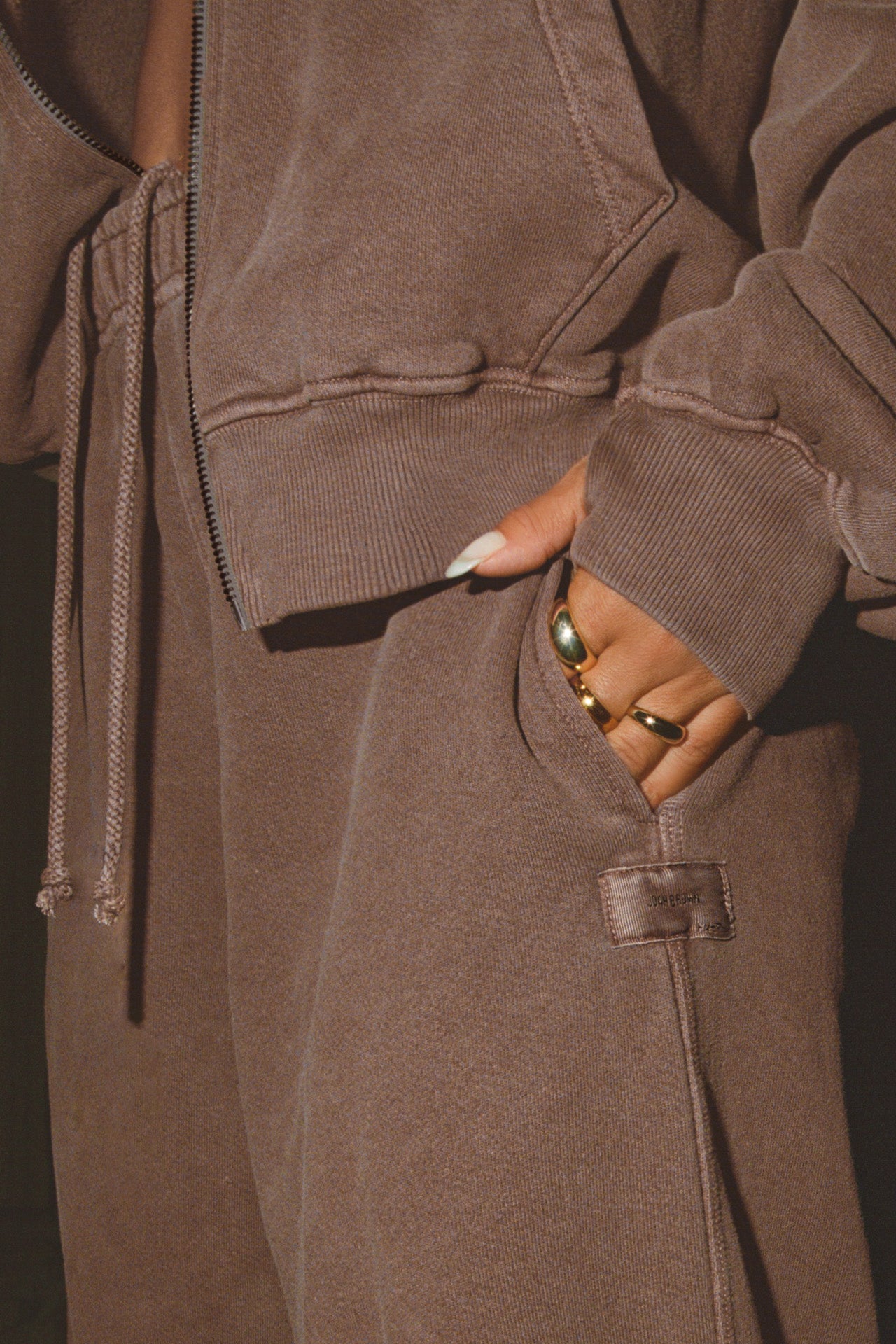 Close up detail side view of model from the waist down posing in the relaxed fit cedar french terry Oversized Straight Leg Jogger with an elastic waistband, hidden drawstring, pocket details and a custom Joah Brown patch