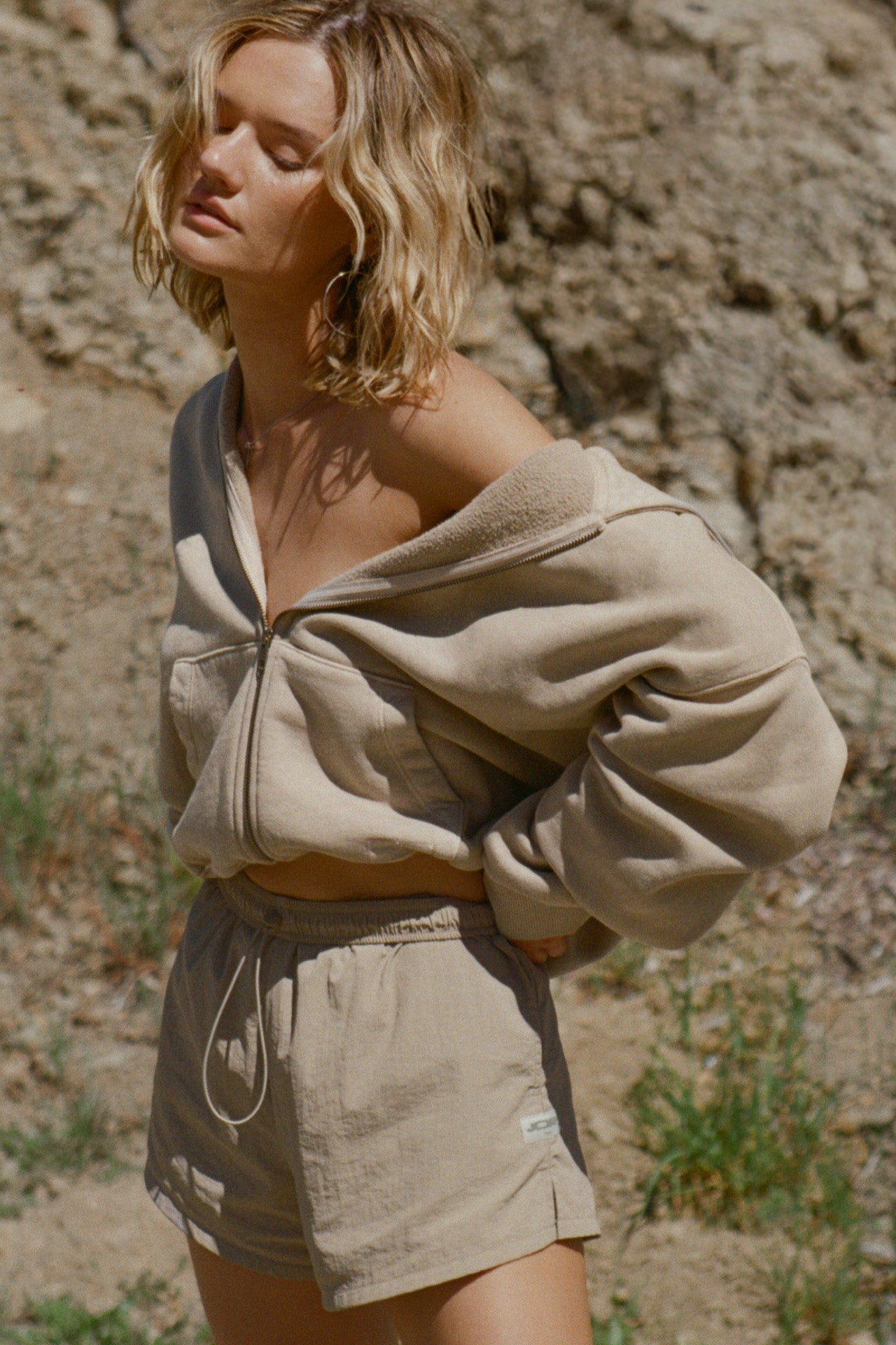 Front view of model posing outside in the oversized comfortable sand french terry Oversized Zip Hoodie with a full length front zip closure, side pockets and thumbholes in the fitted cuffs