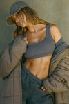 Front view of model posing in the fitted and stretchy smoke flexrib Scoop Neck Bra top with a scoop neckline