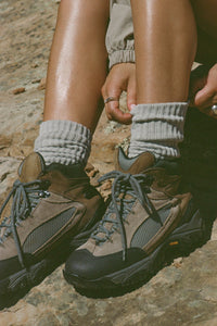 Close up front view of model adjusting the slouchy salt Scrunch Sock with extra long ribbed cuffs