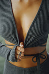 Close up detail front view of model posing in the reversible wrap-around ultra cropped charcoal luxe knit Wrap Cardigan with adjustable ties and fitted sleeves with thumbholes