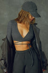 Front view of model posing in the reversible wrap-around ultra cropped charcoal luxe knit Wrap Cardigan with adjustable ties and fitted sleeves with thumbholes