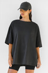Front view of model posing the relaxed fit washed black cotton Oversized Vintage Tee with dropped shoulders and a crew neckline