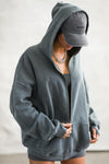 Side view of model posing in the oversized comfortable evergreen french terry Oversized Zip Hoodie with a full length front zip closure, side pockets and thumbholes in the fitted cuffs