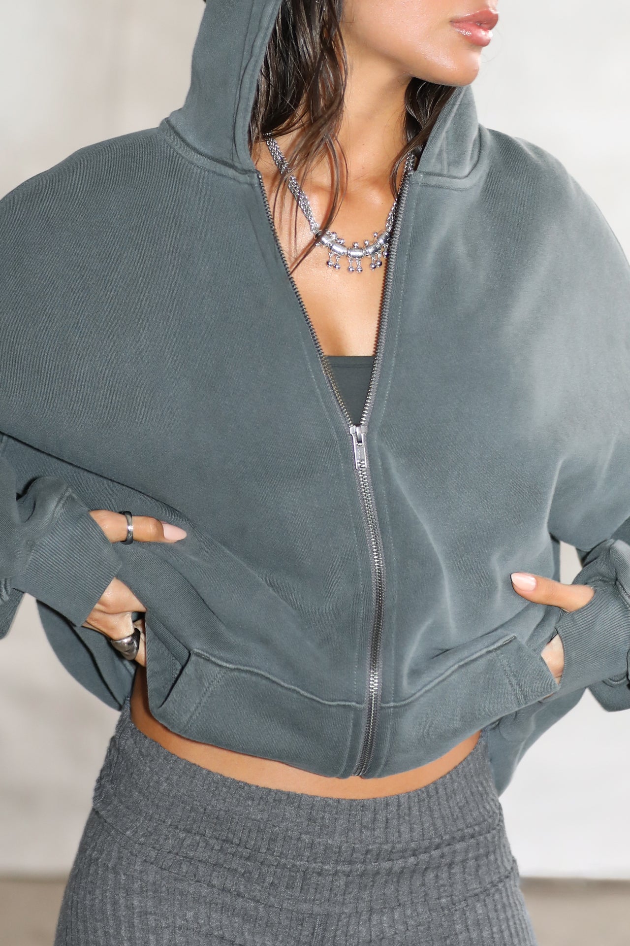 Close up front view of model posing in the oversized comfortable evergreen french terry Oversized Zip Hoodie with a full length front zip closure, side pockets and thumbholes in the fitted cuffs