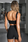 Back view of model posing in the fitted and stretchy black flexrib Scoop Neck Bra top with a scoop back