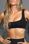 Close up front view of model posing in the fitted and stretchy black flexrib Scoop Neck Bra top with a scoop neckline