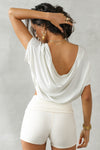 Back view of model posing in the cropped, loose fitting chalk model Slouchy Crop Tee with a wide scoop neckline