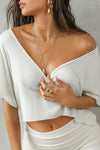 Close up front view of model posing in the cropped, loose fitting chalk model Slouchy Crop Tee with a wide scoop neckline