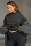 Front view of model posing in the comfortable black french terry Turtleneck Sweatshirt pullover with a side split in the collar and a slightly oversized fit