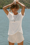 Front view of model posing outside by a lake in the relaxed fit white modal Boyfriend Tee with a crew neckline