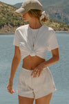 Front view of model posing outside by a lake in the relaxed fit white modal Boyfriend Tee with a crew neckline