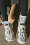 Close up front view of model adjusting the crew-style silver Mini Stripe Sock with ribbed cuffs