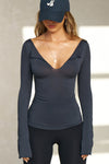 Front view of model posing in the fitted navy modal Notched V Neck Long Sleeve top with a deep notched V-neckline, extra long sleeves and small side slits at the hem