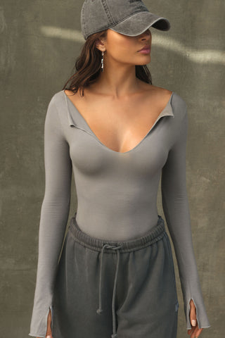 Front view of model posing in the fitted shadow modal Notched V Neck Long Sleeve top with a deep notched V-neckline, extra long sleeves and small side slits at the hem