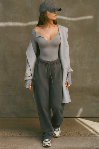 Full body front view of model posing in the fitted shadow modal Notched V Neck Long Sleeve top with a deep notched V-neckline, extra long sleeves and small side slits at the hem