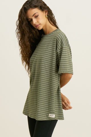 Side view of model posing in the oversized, lightweight forest stripe classic cotton Off-Duty Tee with a crew neckline and dropped shoulders