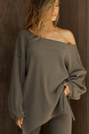 Front view of model posing in the relaxed fit army luxe knit Off Shoulder Tunic with a wide off-the-shoulder neckline and asymmetrical hem