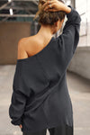 Back view of model posing in the relaxed fit midnight luxe knit Off Shoulder Tunic with a wide off-the-shoulder neckline and asymmetrical hem