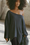 Front view of model posing in the relaxed fit midnight luxe knit Off Shoulder Tunic with a wide off-the-shoulder neckline and asymmetrical hem