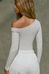 Back view of model posing in the fitted pearl grey rib Off Shoulder Twist Long Sleeve top asymmetrical neckline with a twist detail and off-shoulder design
