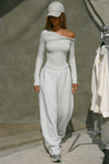 Full body front view of model posing in the fitted pearl grey rib Off Shoulder Twist Long Sleeve top asymmetrical neckline with a twist detail and off-shoulder design