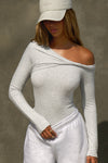 Front view of model posing in the fitted pearl grey rib Off Shoulder Twist Long Sleeve top asymmetrical neckline with a twist detail and off-shoulder design