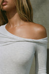 Close up detail front view of model posing in the fitted pearl grey rib Off Shoulder Twist Long Sleeve top asymmetrical neckline with a twist detail and off-shoulder design