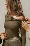 Side view of model posing in the fitted woodland rib Off Shoulder Twist Long Sleeve top asymmetrical neckline with a twist detail and off-shoulder design