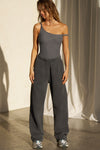 Full body front view of model posing in the fitted shadow rib Off Shoulder Twist Tank with an asymmetrical neckline with a twist detail and off-shoulder design