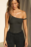 Front view of model posing in the fitted vintage black rib Off Shoulder Twist Tank with an asymmetrical neckline with a twist detail and off-shoulder design