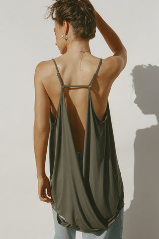 Back view of model posing in the flowy and relaxed spruce modal Open Back Slip Tank with and open back, adjustable straps and back button closures for a customizable fit.