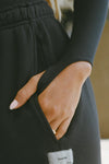 Close up detail view of model posing in the fitted black modal Open Back Turtleneck long sleeve top with thumbholes at the bottom of the sleeves