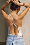 Back view of model posing in the fitted chalk modal Open T-Back Cami with an open t-back design