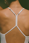 Close up detail back view of model posing in the fitted chalk modal Open T-Back Cami with an open t-back design