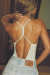 Back view of model posing in the fitted chalk modal Open T-Back Cami with an open t-back design