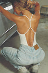 Back view of model posing in the fitted chalk modal Open T-Back Cami with an open t-back design