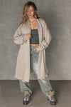 Full body front view of model posing in the knee-length loose fitting sand sherpa Oversized Cardigan with a rolled neckline and extra long sleeves