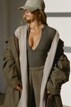 Front view of model posing in the knee-length loose fitting sand sherpa Oversized Cardigan with a rolled neckline and extra long sleeves