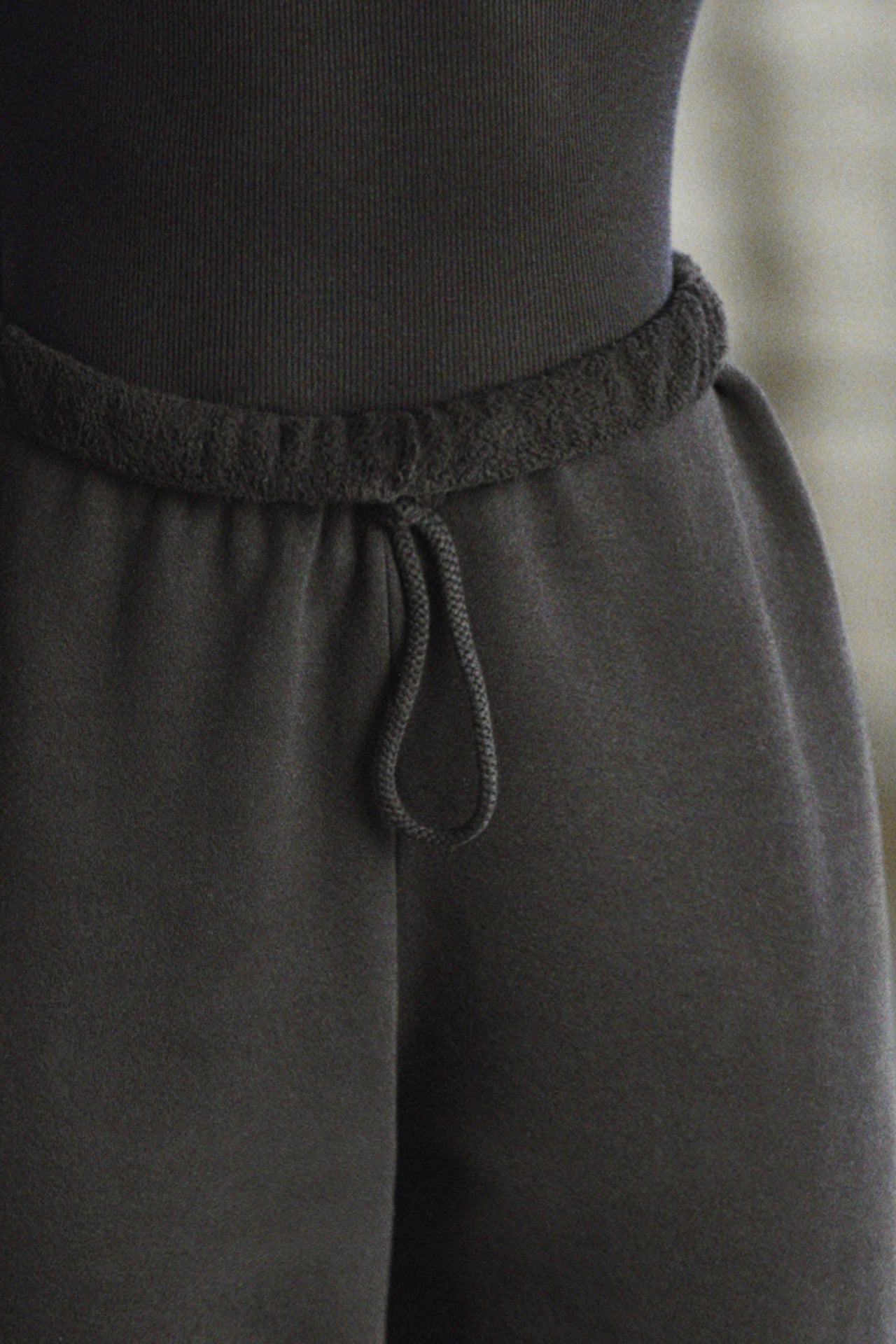 Close up detail front view of model from the waist down wearing the oversized loose fit black french terry Oversized Jogger with an elastic waistband and ankle cuffs