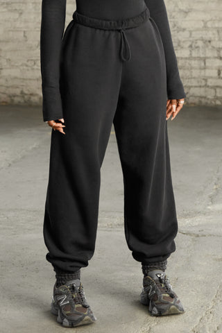 Front view of model from the waist down wearing the oversized loose fit black french terry Oversized Jogger with an elastic waistband and ankle cuffs