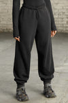 Front view of model from the waist down wearing the oversized loose fit black french terry Oversized Jogger with an elastic waistband and ankle cuffs