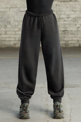 Front view of model from the waist down wearing the oversized loose fit black french terry Oversized Jogger with an elastic waistband and ankle cuffs
