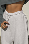 Close up detail front view of model from the waist down posing in the oversized loose fit pearl grey french terry Oversized Jogger with an elastic waistband and ankle cuffs