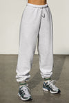 Front view of model from the waist down posing in the oversized loose fit pearl grey french terry Oversized Jogger with an elastic waistband and ankle cuffs